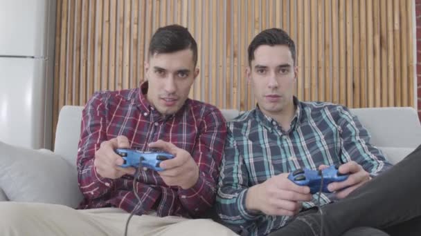 Retrato de hombres caucásicos adultos felices jugando videojuegos. Sonriendo hermanos gemelos dando choco cinco como ganar en la competencia. Ocio, estilo de vida, felicidad . — Vídeos de Stock