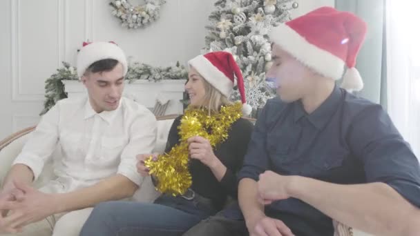 Twin brothers sitting on both sides of pretty girl and talking. Smiling young woman listening to her friends converation. Holidays, Christmas, happiness. — Stock Video