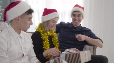 İkiz kardeşlerden Noel hediyesi alan güzel pozitif kız portresi. Yetişkin adamlar yeni yıl arifesini arkadaşlarıyla kutluyorlar. Mutluluk, yaşam tarzı, rahatlık..