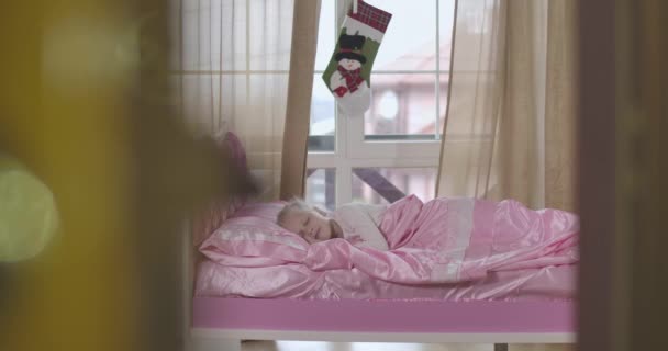 Skjuta genom dörröppningen, Santa Claus kommer in i rummet och sitter på rosa säng när söt vit flicka sover. Julen, julen, barndomen, miraklet. Cinema 4k Prores Hq. — Stockvideo