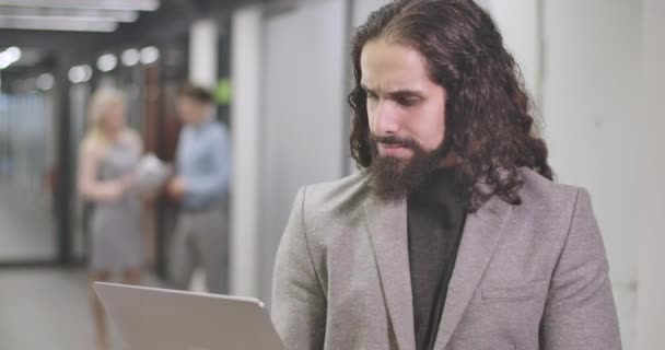 Gros plan d'un jeune homme du Moyen-Orient tapant sur un clavier d'ordinateur portable, regardant la caméra et souriant. Un employé de bureau confiant debout dans un espace ouvert. Affaires, succès, travail acharné. Siège social Cinema 4k ProRes . — Video