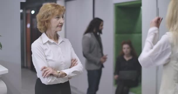 一个严肃的中年白人妇女的画像，她双手叉腰站在空旷的办公室里，转身走向接待处，拿着文件。 在工作场所自信的Ceo 。 电影4k Prores Hq. — 图库视频影像