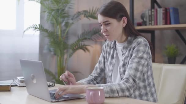 Retrato de menina caucasiana irritada digitando no teclado do laptop. Freelancer feminino irritado discutindo online. Trabalho à distância, freelance, ocupação profissional . — Vídeo de Stock