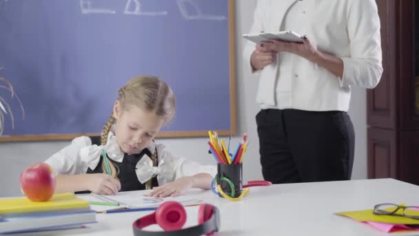 Irreconocible hembra caucásica tutor enseñanza linda chica en casa. Niño inteligente que estudia con profesor privado. Lección, educación, diligencia . — Vídeo de stock