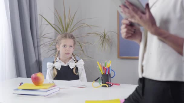 Estudante branca bonito pulando para cima da mesa e fazendo gesto de vitória. Tutor feminino irreconhecível em primeiro plano à direita. Educação, felicidade, inteligência . — Vídeo de Stock