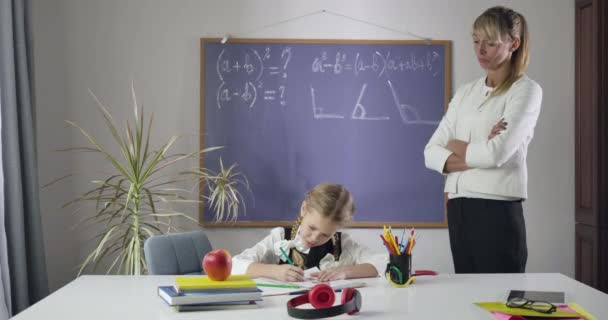 Ein strenger kaukasischer Lehrer betrachtet die Zeichnung einer Schülerin in einem Schulheft. Grundschüler lernen zu Hause. Privatunterricht, Fleiß, Lernen. kino 4k prores hq. — Stockvideo