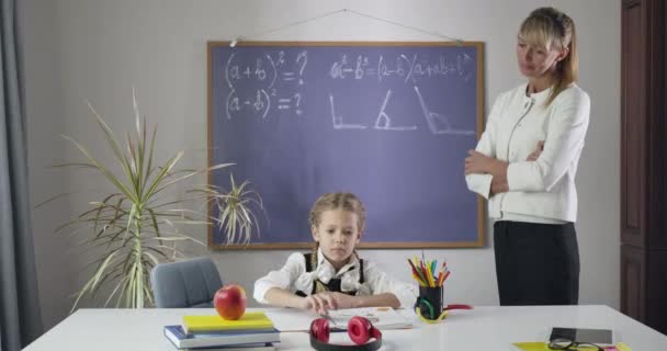 Impresionado maestro caucásico viendo anuncio colegiala ponerse los auriculares y sacudir la cabeza. Niña alegre portándose mal como estudiando en casa. Educación, aprendizaje. Sede del cine 4k ProRes . — Vídeos de Stock