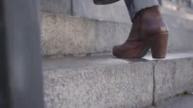 Kot pantolonlu, kahverengi çizmeli, merdivenlerden çıkan beyaz kadın bacakları. Yaşam tarzı, acelesi, iş adamları.