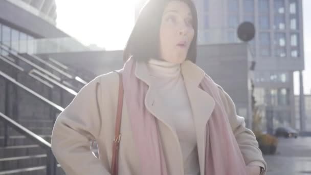 Веселий брюнетт Кавказька жінка співає і танцює на сонці так само, як стоїть на вулицях міста. Позитивна пані відпочиває на відкритому повітрі перед діловою зустріччю. Життя, щастя, успіх. — стокове відео