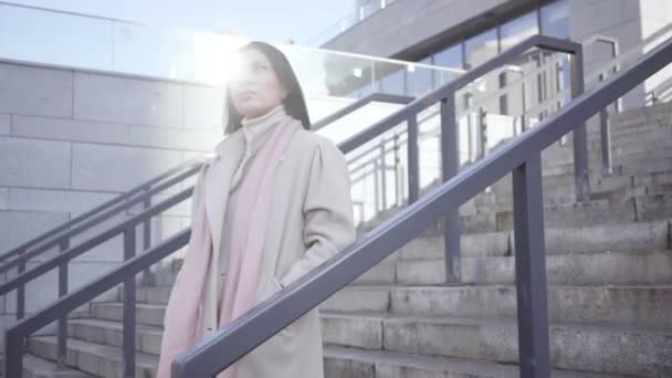 Telecamera in movimento per adulti donna caucasica in piedi sulle scale e in attesa di qualcuno. Ritratto di donna d'affari seria vestita con elegante cappotto. Incontri, affari, stile di vita . — Video Stock