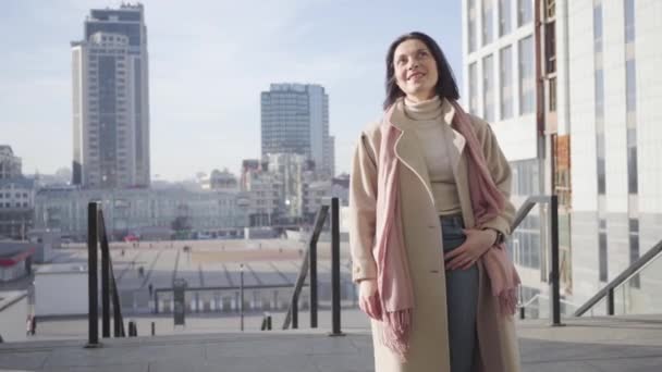 Fröhliche kaukasische Frau, die an einem sonnigen Herbsttag in der Stadt steht und lächelt. positive Frau genießt sonnigen Tag in der Stadt. Lebensstil, Stolz, Erfolg. — Stockvideo