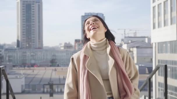 Zbliżenie radosnej białej kobiety stojącej w mieście w słoneczny jesienny dzień. Uśmiechnięta kobieta ciesząca się słonecznym dniem na świeżym powietrzu. Styl życia, duma, sukces. — Wideo stockowe