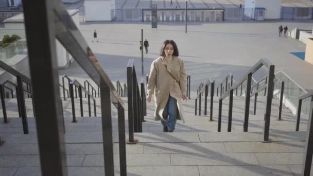 Portret van een drukke blanke vrouw die de trap op rent in de stad en even rust neemt. Uitgeputte brunette zakenvrouw te laat voor de ontmoeting. Banen, vergaderingen, levensstijl. — Stockvideo