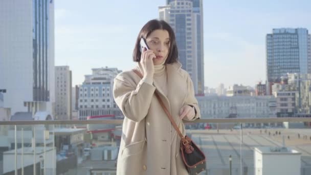 Mittlere Aufnahme einer erfolgreichen kaukasischen Frau, die am Telefon spricht. junge brünette Dame, die auf der Straße steht. Lebensstil, Überarbeitung. — Stockvideo