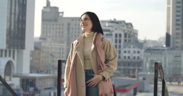 Morena segura mujer caucásica de pie en la calle de la ciudad y mirando hacia otro lado. Mujer de negocios sonriente disfrutando de un día soleado en el fondo de rascacielos. Sede del cine 4k ProRes . — Vídeos de Stock