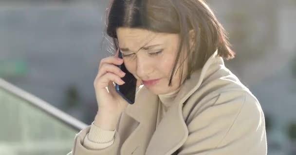 Foto close-up dari wanita berambut cokelat Kaukasia yang sedih berbicara di telepon. Indah stres pengusaha wanita memiliki masalah komunikasi. Sinema 4k ProRes HQ . — Stok Video
