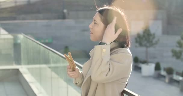 Sidovy över ung brunett vit kvinna som håller smörgås och pratar. Lyckade affärer slady att ha paus på stadens gata. Cinema 4k Prores Hq. — Stockvideo