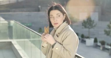 Esmer, beyaz bir kadın caddede duruyor ve aç gözlerle sandviç yiyor. Şehir sokaklarında mola veren tombul iş kadınının portresi. Sinema 4k Prores Merkezi.