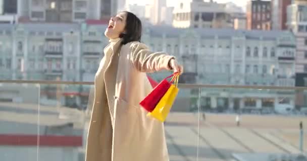 Mujer caucásica feliz girando con bolsas de compras de colores. Joven adicto a las compras sonriente disfrutando del día en la calle de la ciudad con compras. Compras, estilo de vida. Sede del cine 4k ProRes . — Vídeos de Stock