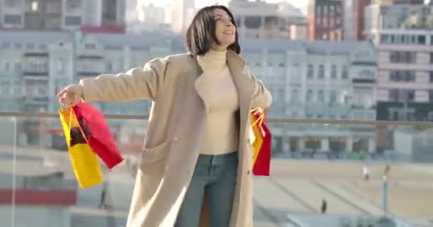 쾌활 한 백인 여성 이 화려 한 쇼핑백 과 노래로 춤을 추고 있습니다. 도시의 거리에서 물건을 사는 것을 즐기는 행복 한 가게 주인. 쇼핑 과 생활 양식. 영화 4K 전립선 HQ. — 비디오