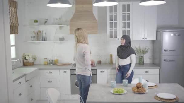 Femme musulmane dans le hijab se disputant avec un ami caucasien blond à la maison. Deux femmes se disputant à l'intérieur. Incompréhension, communication multiethnique, problèmes relationnels . — Video