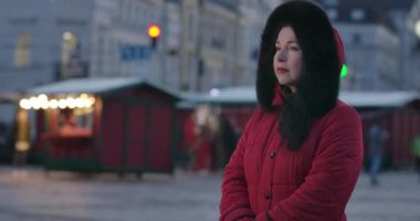 Şehir caddesinde dikilip saati kontrol eden sinirli beyaz kadın portresi. Orta yaşlı bir bayan şehir pazarında birini bekliyor. Yaşam tarzı, boş zaman, toplantılar. Sinema 4k Prores Merkezi.