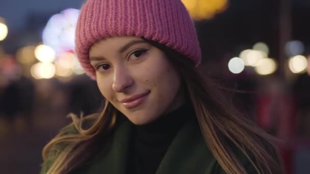 Retrato de cerca de la joven hermosa mujer caucásica en sombrero rosa de pie al aire libre y sonriendo. Una chica encantadora pasando la noche al aire libre. Descanso, ocio, estilo de vida . — Vídeo de stock