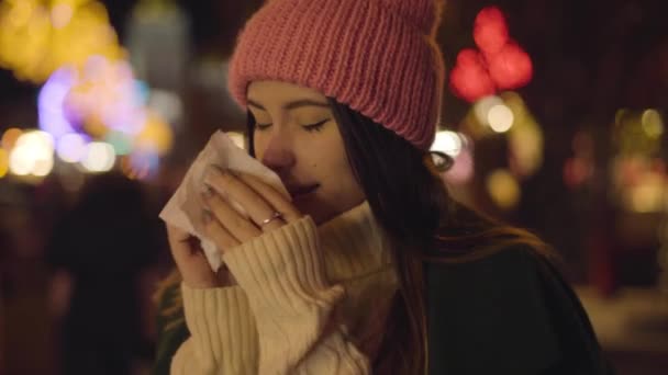 Porträt eines kranken kaukasischen Mädchens, das sich die Nase reibt und im Freien niest. junge schöne Frau, die auf dem Stadtmarkt steht und wartet. Lebensstil, Tagungen, Freizeit. — Stockvideo