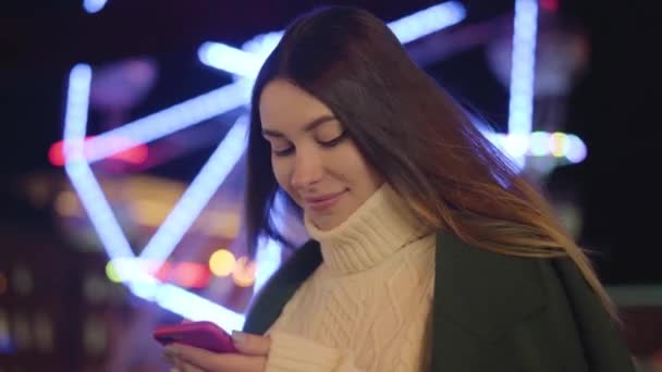 Portrait of beautiful Caucasian woman holding smartphone and smiling. Charming young girl spending freee time outdoors on city market. Lifestyle, leisure, communication. — ストック動画