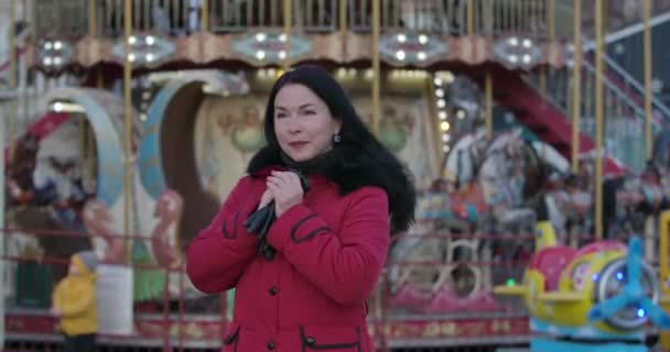 Portrait of middle-aged Caucasian woman in red coat putting on leather gloves. Charming adult lady standing on city market and waiting. Leisure, lifestyle, happiness. Cinema 4k ProRes HQ. — 비디오