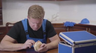 Kafkasyalı genç tesisatçı portresi. Kızıl saçlı adam sandviç ve termos şişesini çıkarıyor. İş yerinde profesyonel dinlenme. Yaşam tarzı, uğraş, dinlenme.