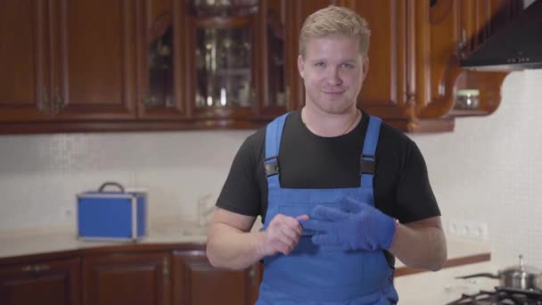 Portrait of handsome Caucasian man in workrobe taking off glove and showing thumb up. Young repairman satisfied with the result of his work. Professional occupation, warranty service. — Stock Video