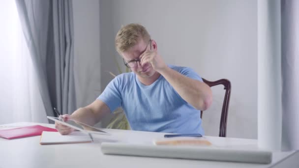 Retrato de empresário caucasiano confiante em óculos olhando para a tela do tablet e tomando notas. Homem ruivo sério a escrever tarefas futuras. Sucesso, motivação, estilo de vida . — Vídeo de Stock