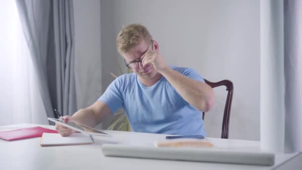 Retrato de hombre de negocios caucásico confiado en gafas de vista mirando la pantalla de la tableta y tomando notas. Un pelirrojo serio anotando tareas futuras. Éxito, motivación, estilo de vida . — Vídeos de Stock