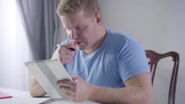 Πορτρέτο του στοχαστικού Καυκάσου που κοιτάζει την οθόνη του tablet και γράφει σημειώσεις. Έξυπνος νέος επιχειρηματίας σκέφτεται την εργασία του. Επιτυχία, κίνητρο, τρόπος ζωής. — Αρχείο Βίντεο