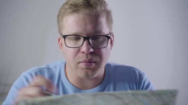 Gros plan portrait de rousse architecte caucasien en lunettes assis à la table avec carte et prise de notes. Homme professionnel travaillant à l'intérieur. Professionnel, profession, travail, style de vie . — Video