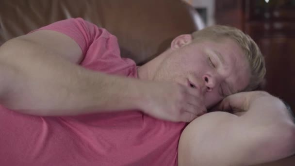 Close-up of redhead Caucasian man sleeping on couch at home. Lazy young guy resting alone at home. Leisure, resting, lifestyle. — 비디오