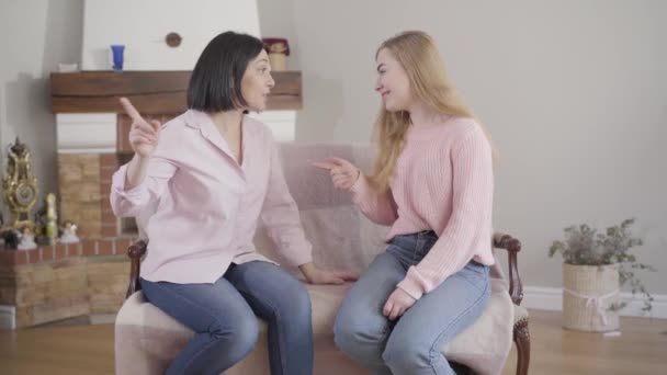Ung brunett vit kvinna pratar känslomässigt med blond flicka inomhus. Mor vilar med dotter hemma. Förtroende, tillit, familjeförhållande. — Stockvideo