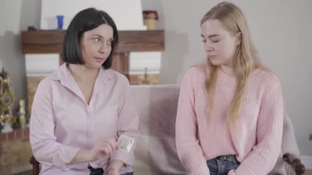 Young brunette Caucasian mother giving her teenage daughter condom. Wise woman taking care of her adult child. Trust, reliance, confidence. — Stock Video