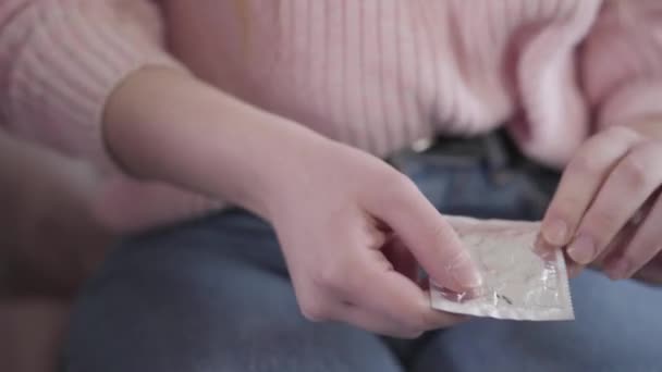 Close-up van jonge vrouwelijke blanke handen die condoom vasthouden en in hun zak steken. Onherkenbaar tienermeisje met anticonceptie. Bescherming, vertrouwen, preventie. — Stockvideo