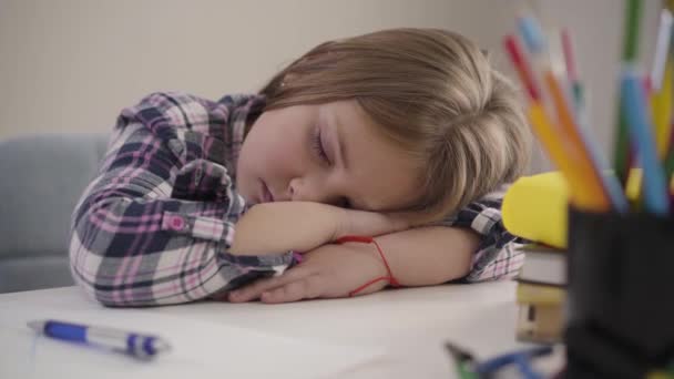 Nahaufnahme Porträt eines müden kaukasischen Schulmädchens, das auf dem Tisch schläft. Erschöpftes Kind schläft ein, während es Hausaufgaben macht. Bildung, Überlastung. — Stockvideo