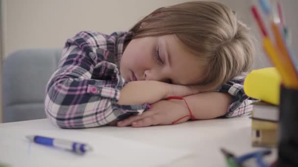 Kamera liikkuu nukkuvan tytön ympäri vasemmalta oikealle. Lähikuva väsynyt koulutyttö nukkuu pöydässä. Ylikuormitus, koulutus, kotitehtävät . — kuvapankkivideo