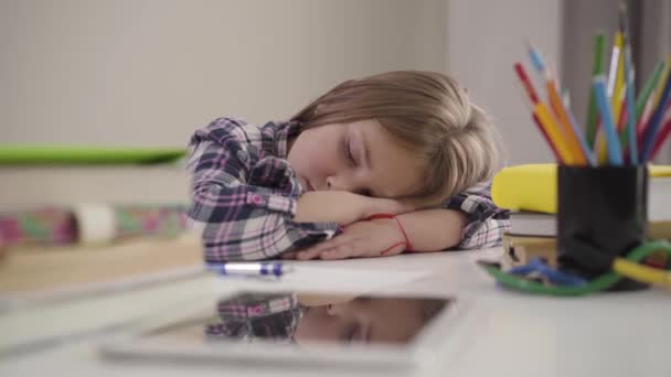 Retrato de una hermosa chica caucásica durmiendo en la mesa. Colegiala morena cansada sentada en la mesa con la cabeza en las manos. Sobrecarga, educación, tarea. Cámara moviéndose de derecha a izquierda . — Vídeos de Stock