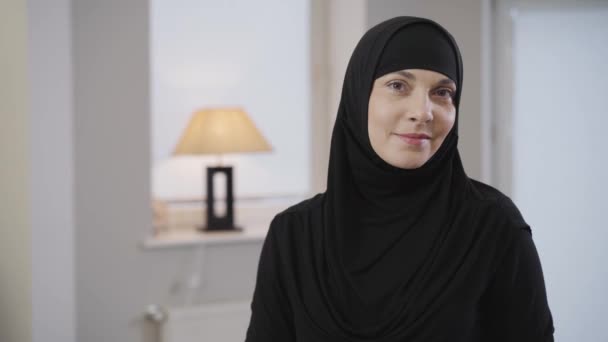 Bela senhora muçulmana em preto tradicional hijab olhando para a câmera e sorrindo. Retrato de bela senhora com olhos castanhos. Povo oriental, tradições. Câmera movendo-se da direita para a esquerda . — Vídeo de Stock