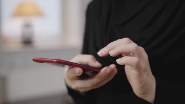 Primer plano de las manos femeninas desplazándose en el teléfono inteligente. Mujer musulmana joven con ropa negra usando teléfono móvil. Sociedad moderna, cultura oriental . — Vídeos de Stock