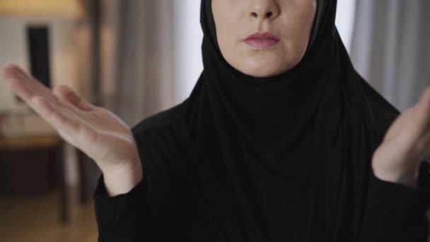 Close-up de mulher muçulmana irreconhecível dobrar as mãos e rezar. Jovem senhora oriental a falar com Deus em casa. Religião, estilo de vida, cultura . — Vídeo de Stock