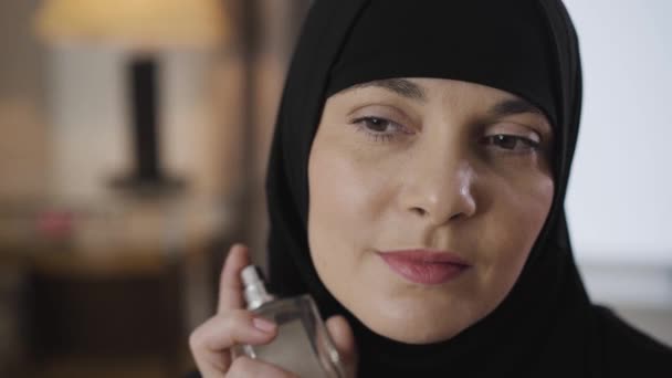 Close-up de bela jovem muçulmana aplicando perfume. Mulher atraente em hijab tradicional se preparando para sair. Beleza, cosméticos, cuidado . — Vídeo de Stock