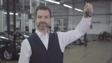 Başarılı beyaz sakallı adam arabanın anahtarlarını sol elinde tutuyor ve evet diyor. Kendine güvenen araba sahibi onarımdan sonra otomobili geri alıyor. Garanti servisi, araba işi.