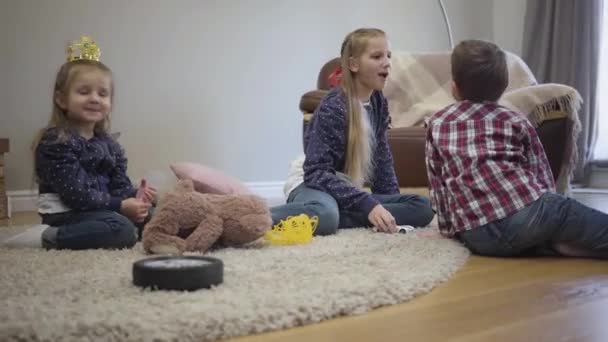 Porträtt av vit tonårstjej som leker med lillebror och syster hemma. Äldre syster tillbringar helger med syskon inomhus. Fritid, livsstil, lycka. — Stockvideo