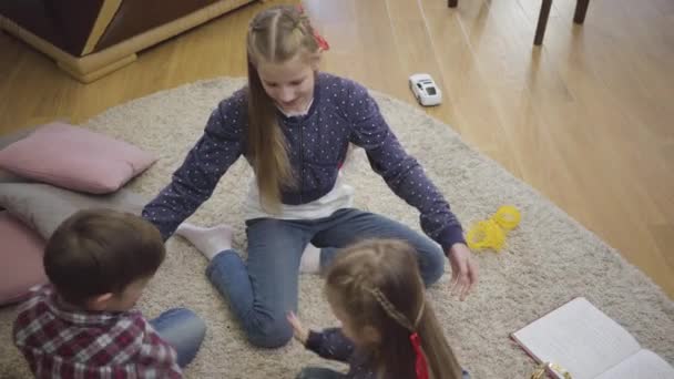 Ovanifrån av glada vita systrar och bror som spelar klappande händer. Leende barn som har roligt hemma. Fritid, enhet, barndom. — Stockvideo